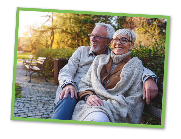 Smiling senior couple sitting on the bench in the park together enjoying retirement.