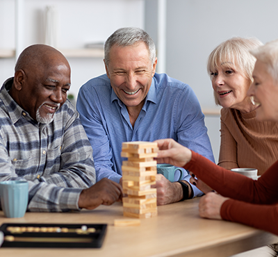 Multiracial senior men and women playing jenga at nursing home.