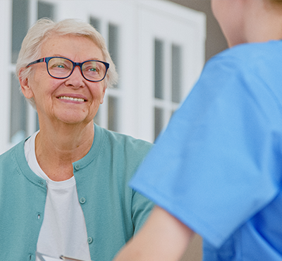 Positive senior lady nods head listening to caregiver recommendations in light office